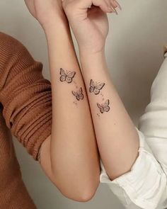 two women with matching tattoos on their arms, both have butterflies tattooed on the arm