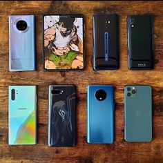 five different models of cell phones lined up on a wooden table with one being an older model