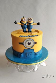 a yellow and blue cake with two minion figures on top