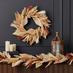 a wreath on top of a mantle next to candles