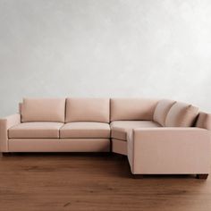 a beige couch sitting on top of a hard wood floor next to a white wall