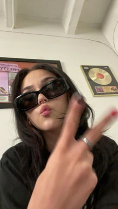 a woman wearing sunglasses making a peace sign with her fingers and finger to the side