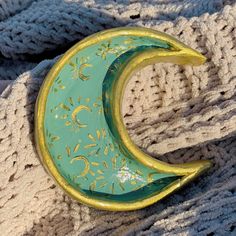 a green and gold crescent brooch sitting on top of a sweater