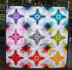 a multicolored quilt is hanging on a fence