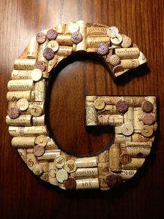 the letter c made out of wine corks on a wooden table with a brown background