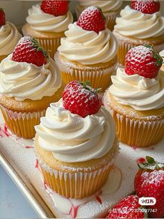 there are many cupcakes with white frosting and strawberries on the top