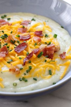 a white bowl filled with mashed potatoes topped with bacon and cheddar cheese