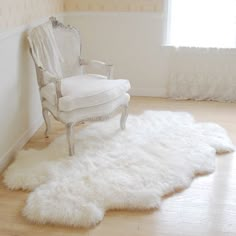 a white chair sitting on top of a hard wood floor next to a rug covered in sheepskin