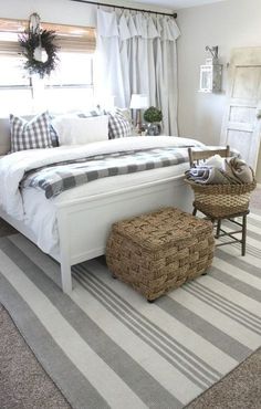 a white bed sitting on top of a rug next to a chair and ottoman in a bedroom