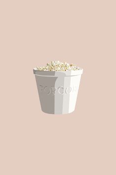 a white cup filled with popcorn on top of a pink background