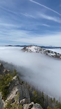 the mountain is covered in low lying clouds and trees, with mountains in the distance