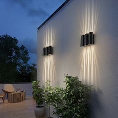 two lights on the side of a building next to a potted plant