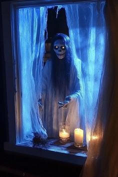 a person dressed as a ghost standing in front of a window with candles on the windowsill