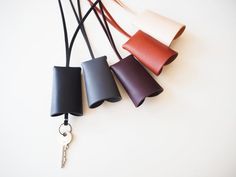 four different colors of leather are hanging on a white wall with a keychain