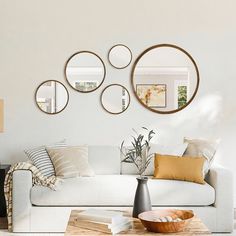 a living room with white couches and mirrors on the wall above it's coffee table