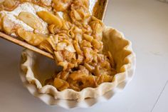 a pie crust with apples and powdered sugar in it on a white table top