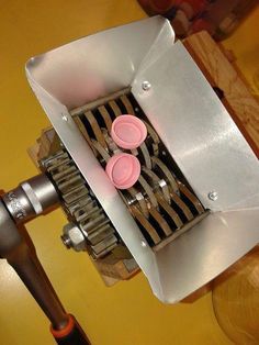 a machine that is sitting on top of a wooden table with two pink cups in it