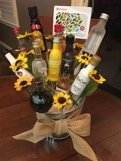 a vase filled with liquor bottles and sunflowers on top of a wooden table