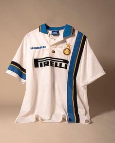 a white shirt with blue and yellow stripes on the front is hanging from a hanger