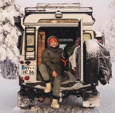 a man sitting in the back of a vehicle with snow on it's tires