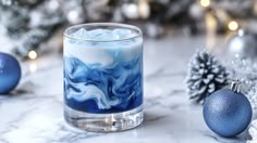 a glass filled with liquid sitting on top of a marble counter next to christmas decorations