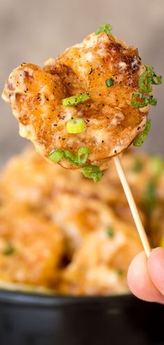 a hand holding up a skewer of chicken and broccoli covered in cheese