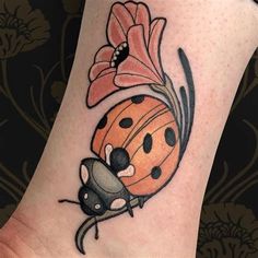 a ladybug tattoo on the ankle with a flower