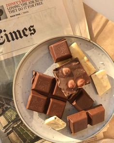 some pieces of chocolate sitting on top of a plate next to an old paper and newspaper