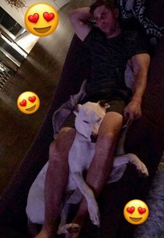 a man sitting on top of a couch next to a white dog with red hearts