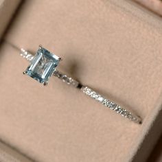 an engagement ring with a blue topazte surrounded by white diamonds in a box