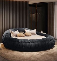 a large round bed in the middle of a room with pillows on top of it