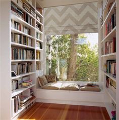 a window seat in the corner of a room with bookshelves full of books