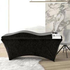 a black bath tub sitting on top of a wooden floor next to a white chair