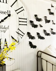 a clock that is on the wall next to a bed with yellow flowers in front of it