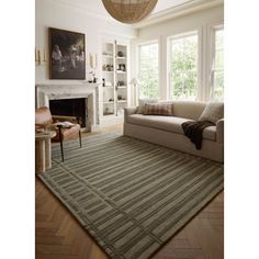 a living room filled with furniture and a large rug on top of a hard wood floor