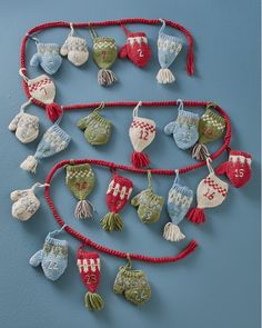 knitted mittens and gloves hanging on a blue wall with red string attached to them