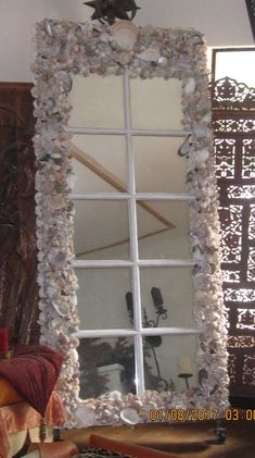 a mirror that is sitting on top of a table in front of a wall with shells