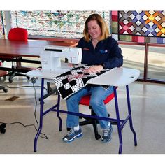 a woman sitting at a table with a sewing machine