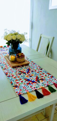 the table is set with flowers, candles and a decorative runner on top of it