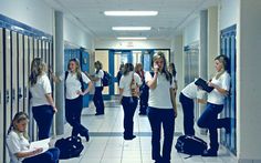 a group of women standing in a hallway next to lockers