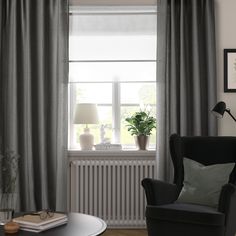 a living room filled with furniture and a window covered in grey drapes, next to a coffee table