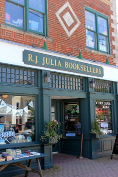 the outside of a book store with tables and benches in front of it on a brick sidewalk