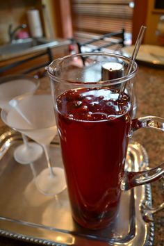 a glass filled with liquid sitting on top of a metal tray