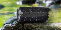 the bluetooth speaker is sitting on top of some rocks and water droplets all over it