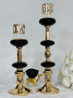 two black and gold candlesticks are sitting next to each other on a white surface