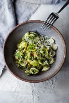 a bowl filled with broccoli and cheese on top of a white table cloth