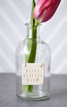 a pink tulip in a glass vase with a tag on it