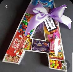 the letter shaped candy box is filled with candies and chocolates as well as a purple bow