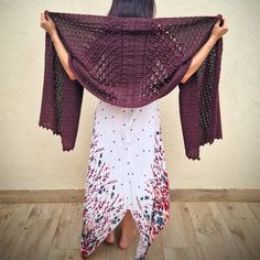 a woman is standing with her back to the camera and holding up a shawl