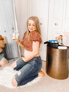 a pregnant woman is sitting on the floor with her stuffed animal and looking at it